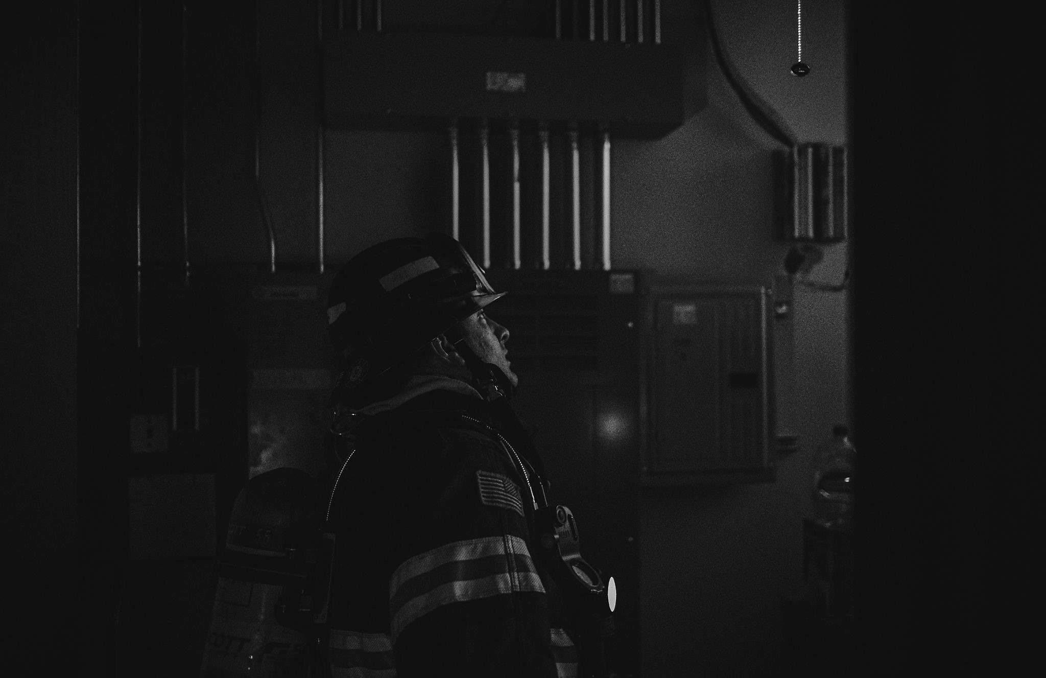 An impactful black and white photo capturing a firefighter in the heroic act of service in a dark room.
