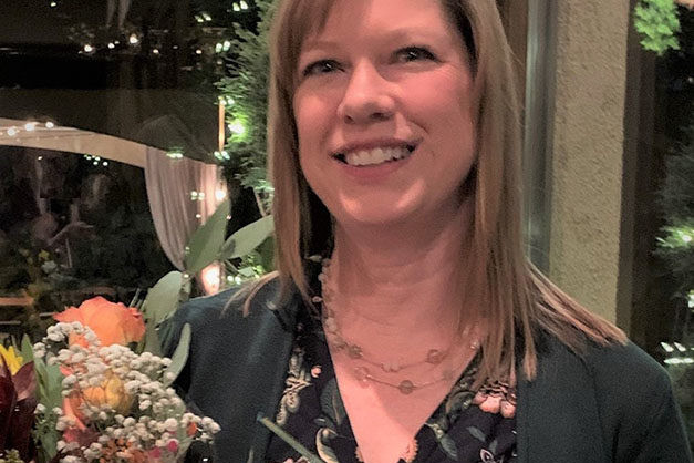 A Valley Regional Fire Authority firefighter holding an award in front of flowers.