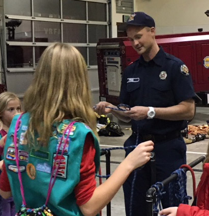 A boy scout helping a girl scout at Valley Regional Fire Authority.