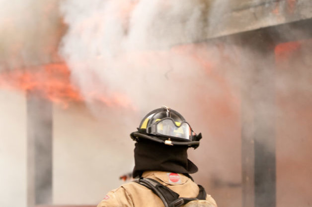 A courageous firefighter from the Fire Department bravely battles a house fire to provide exceptional service.