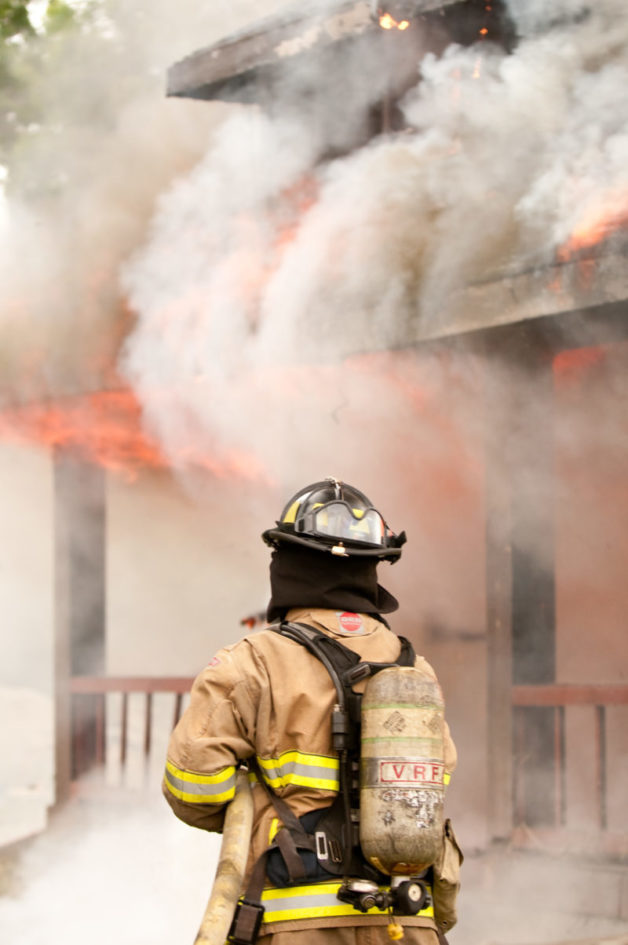 A courageous firefighter from the Fire Department bravely battles a house fire to provide exceptional service.