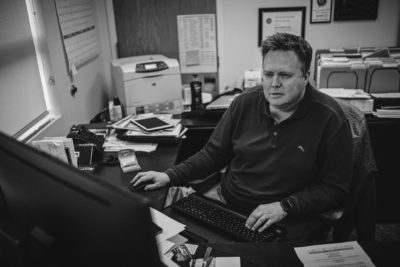 A black and white photo of a man sitting at a desk in the Valley Regional Fire Authority, providing service.