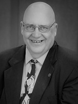 A black and white photo of a smiling bald man who is a firefighter with the Valley Regional Fire Authority.