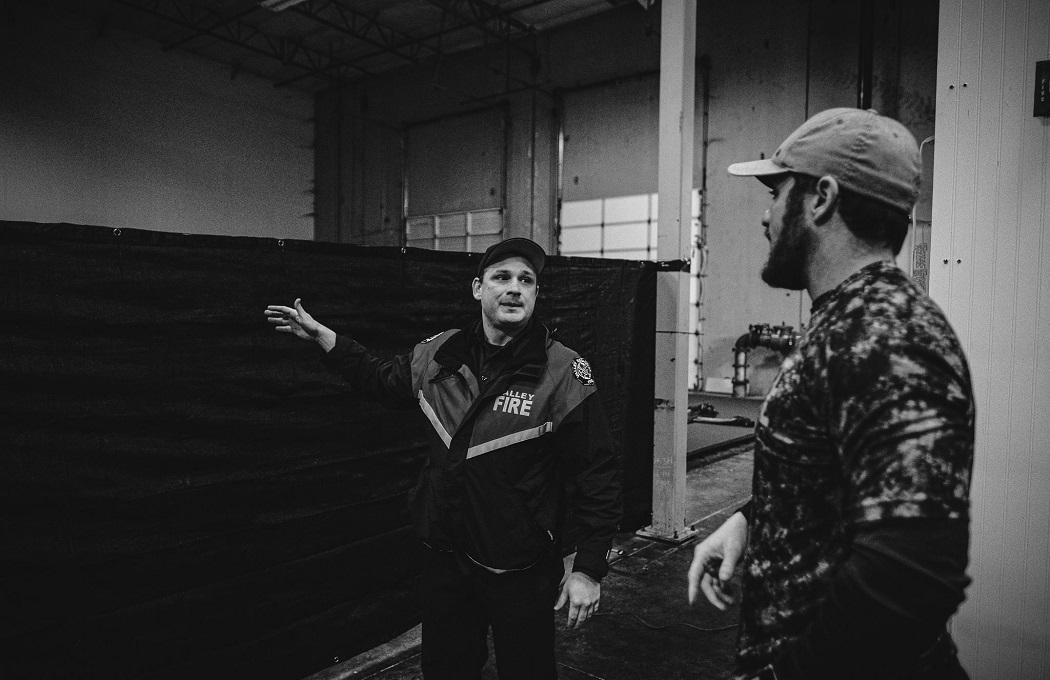 Two men standing next to each other in a Rescue warehouse.