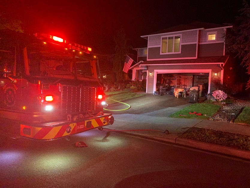 A fire truck from Valley Regional Fire Authority is parked in front of a house at night, manned by a firefighter from the Fire Department.