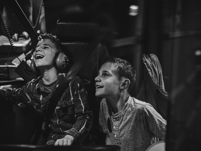 Two boys sitting in a car with Valley Regional Fire Authority headphones on.