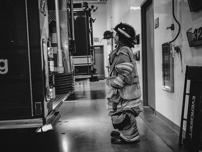 A black and white photo of a firefighter from Valley Regional Fire Authority standing next to a fire truck.