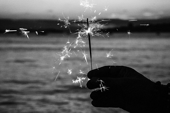 A black and white photo of a person holding a sparkler during a firework service.