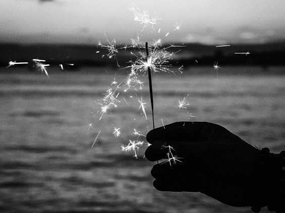 A black and white photo of a person holding a sparkler during a firework service.