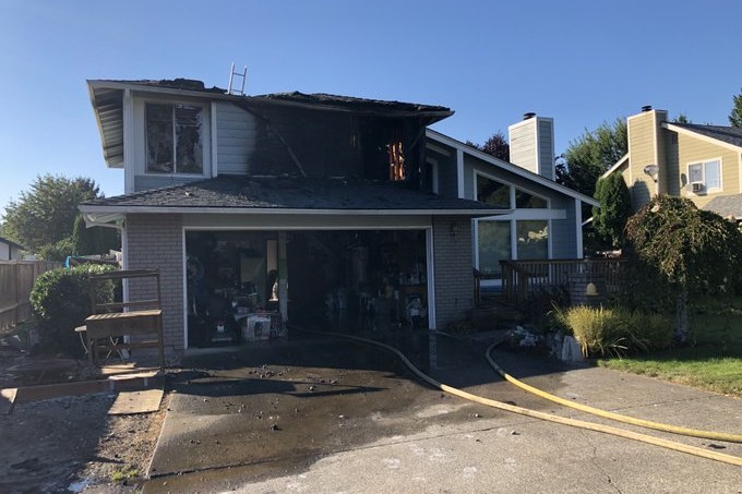 The Fire Department rushes to rescue the house engulfed in flames, with a garage in front.