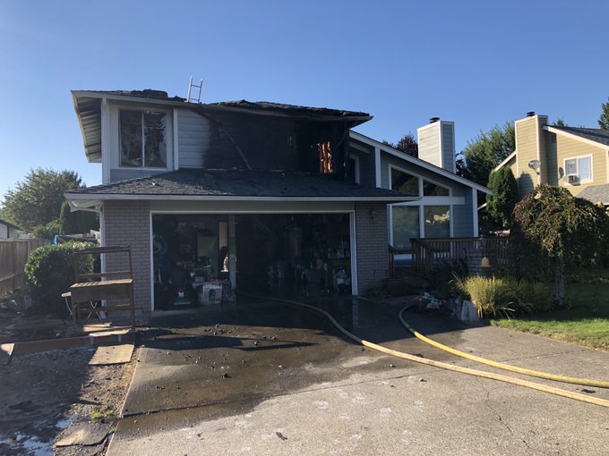 The Fire Department rushes to rescue the house engulfed in flames, with a garage in front.