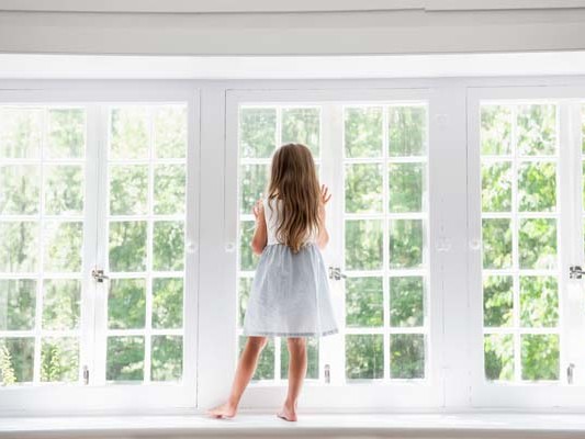 A child standing at a window looking out