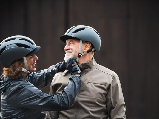 Senior couple adjusting bike helmets for each other