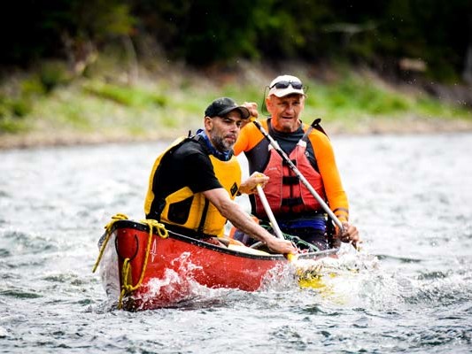 Two men paddling a canoe in rough water