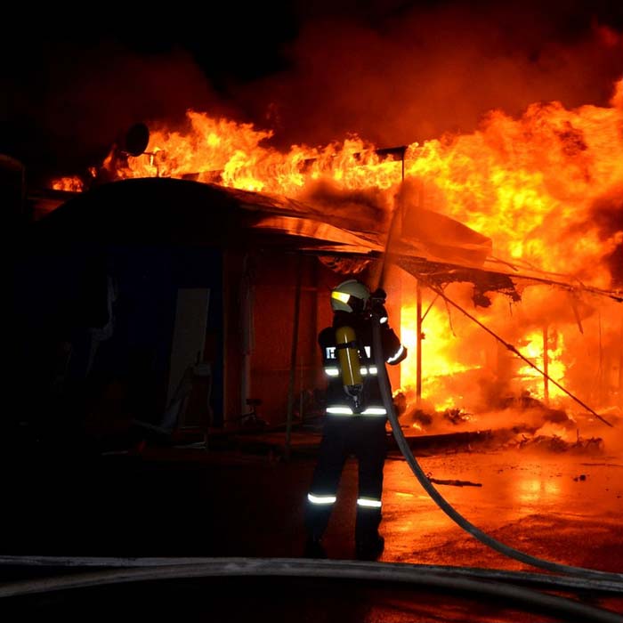 Fire fighter spraying water on a raging house fire