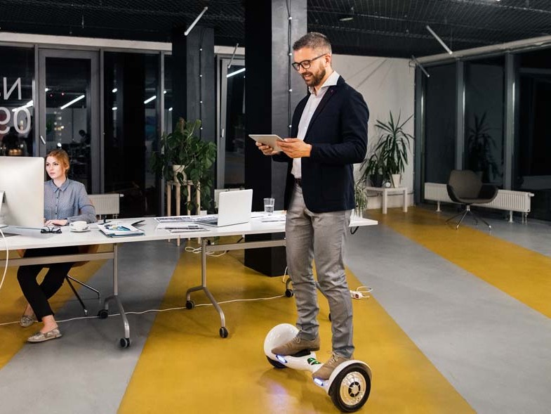 A man standing on a hoverboard in an office, providing service.