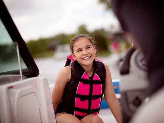 Smiling girl wearing a life jacket on a boat