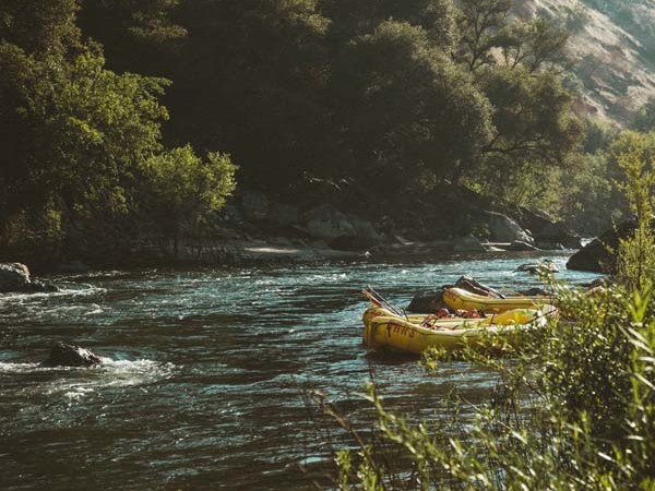 Two tied up river rafts on the side of a beautiful river