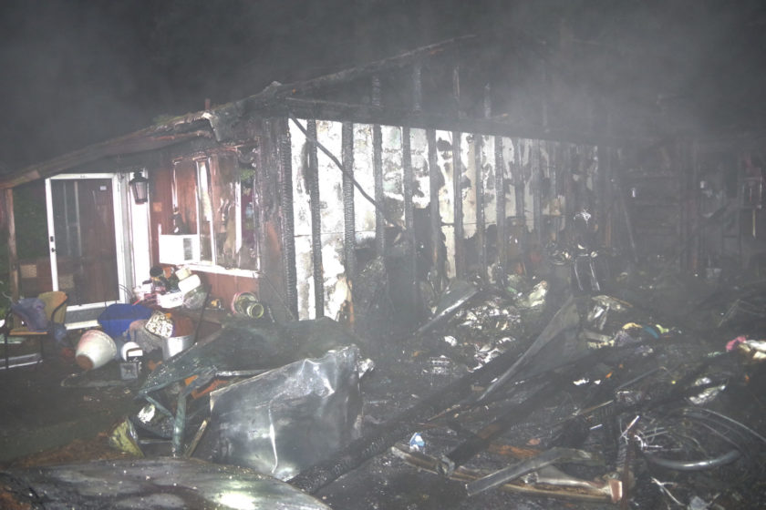 A house is engulfed in flames, while a brave firefighter from the Fire Department rushes in to rescue anyone trapped inside.