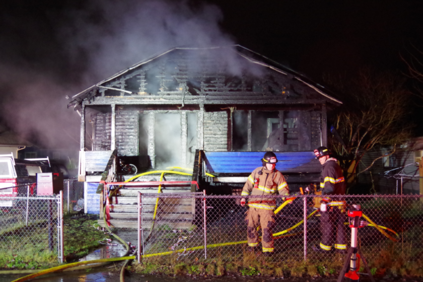 A firefighter from the fire department is standing in front of a house at night, ready to provide rescue services.