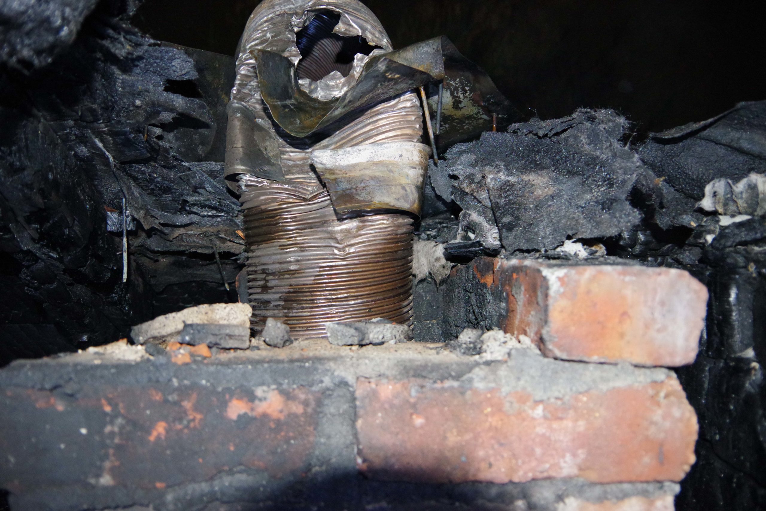 A firefighter with a pipe in a burned out house.