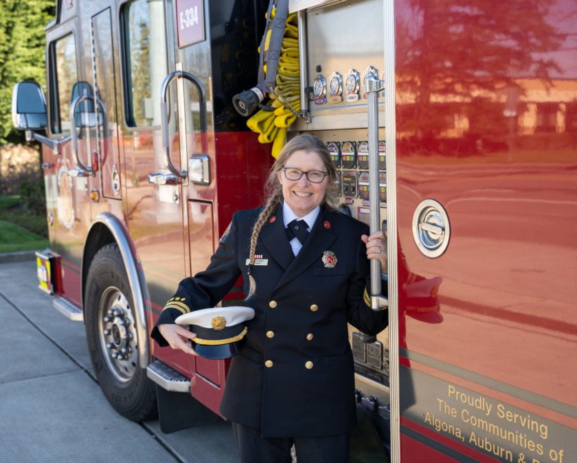 A firefighter in uniform standing next to a fire truck.