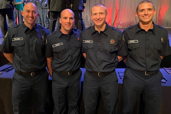 Four firefighters from the Fire Department pose for a photo at an event.