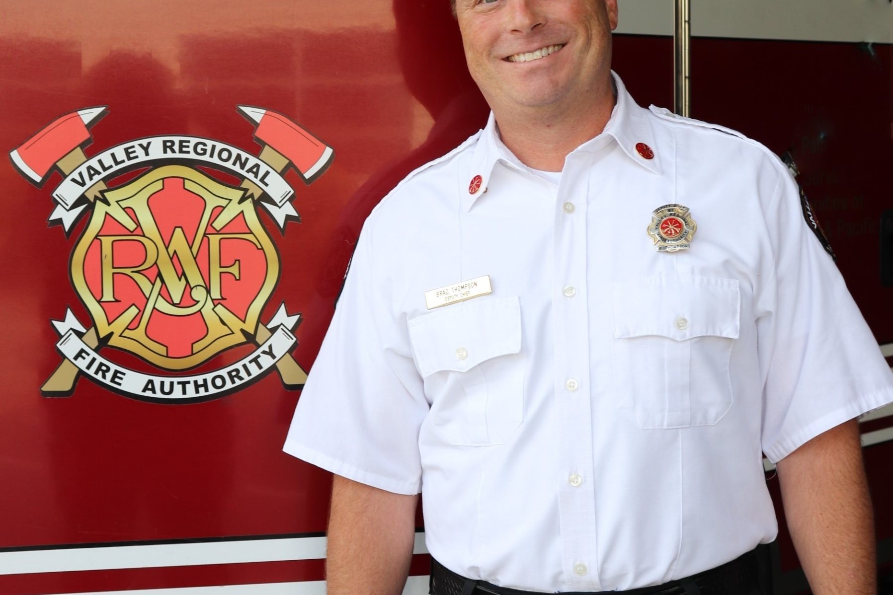 A man standing in front of a fire truck from Valley Regional Fire Authority.