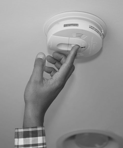 Testing a smoke alarm by pressing it with finger