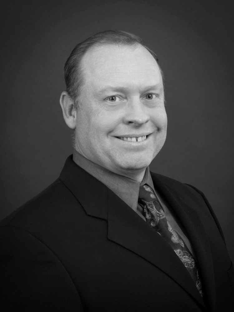 A black and white photo of a man in a suit providing a service.