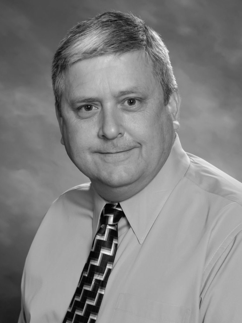 A black and white photo of a man in a tie, representing professionalism and service.