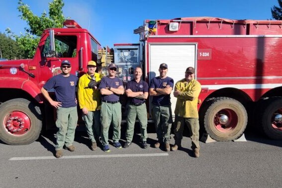 A group of firefighters from the fire department posing in front of a red fire truck, ready to serve and rescue.