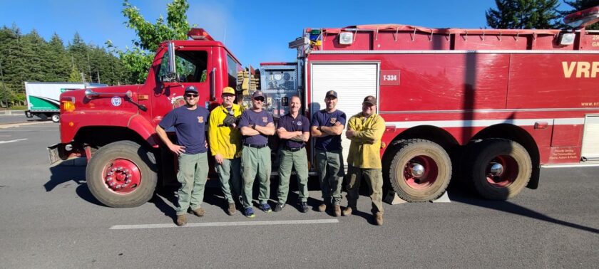 A group of firefighters from the fire department posing in front of a red fire truck, ready to serve and rescue.