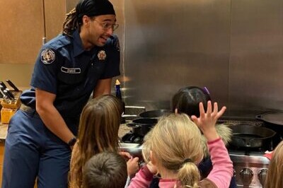 A boy scout cooking with kids in a kitchen, providing a service to teach them valuable cooking skills.