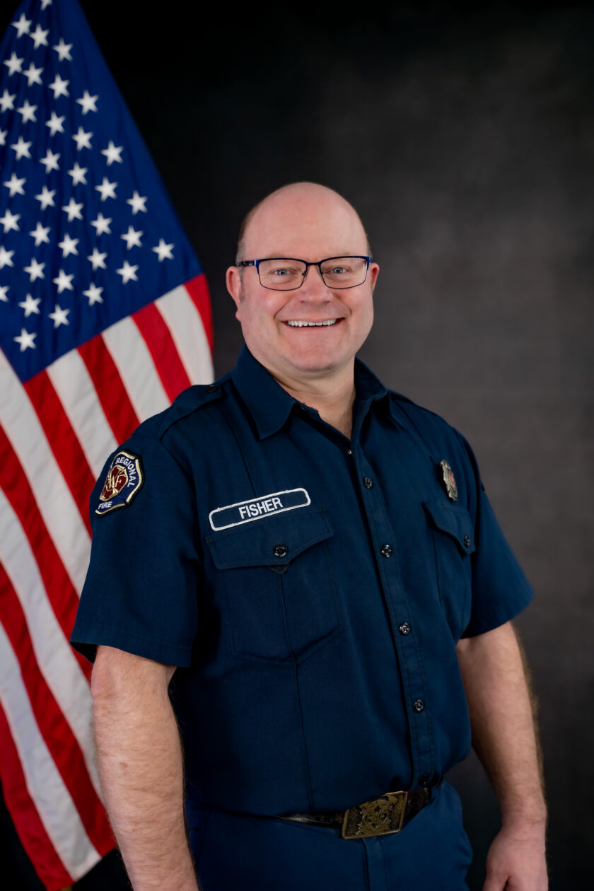 A Service firefighter standing in front of an American flag.