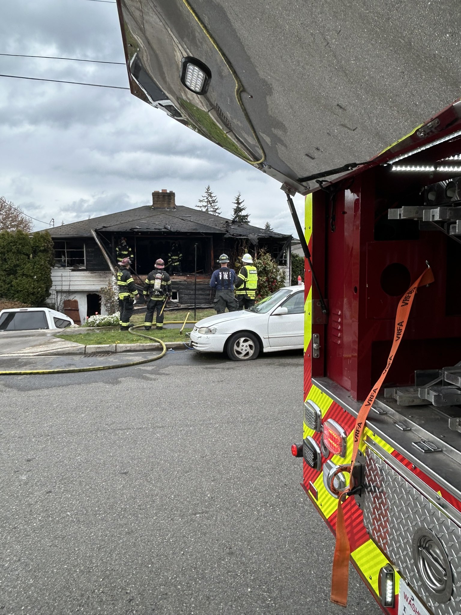 Firefighters rescue one person from a residential fire as seen from the open back of a fire truck.