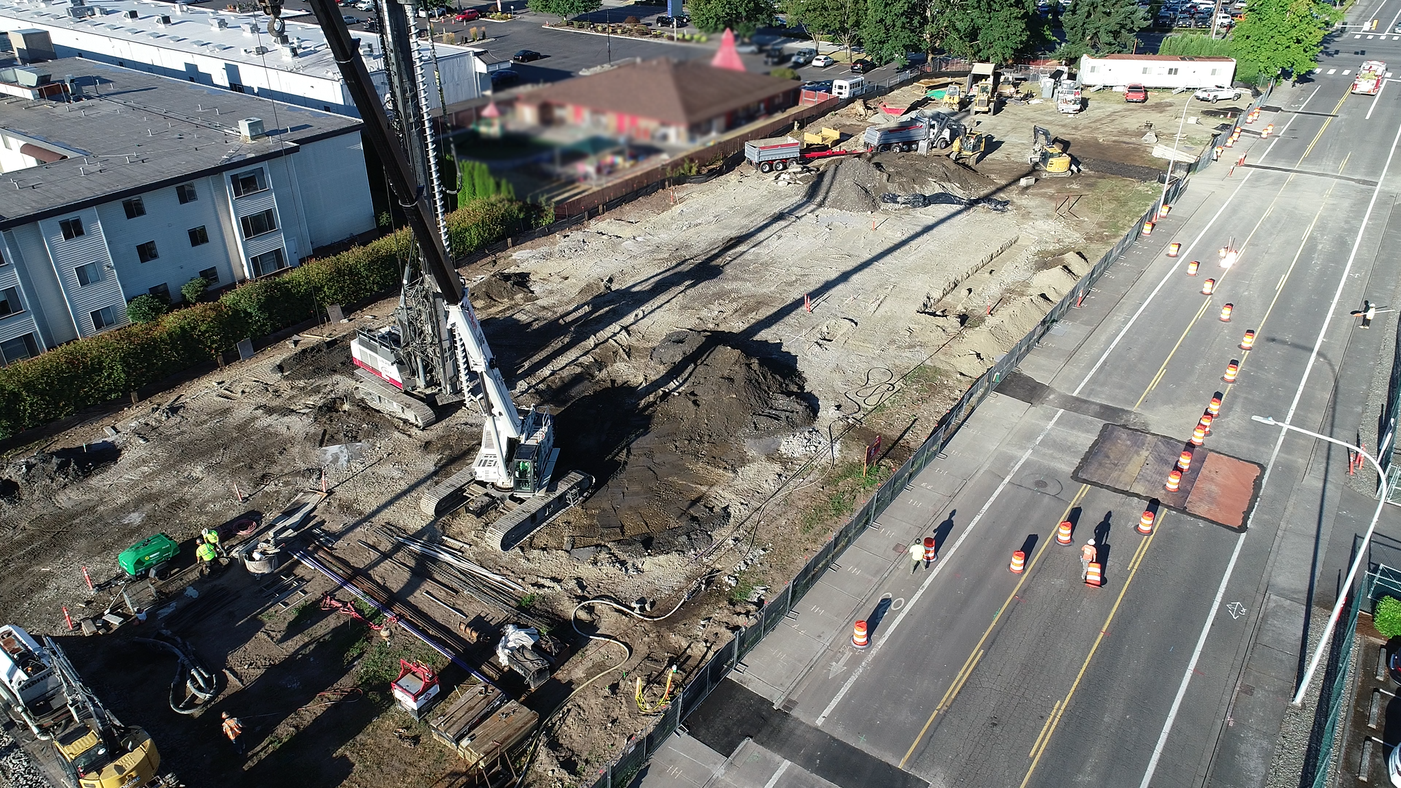 Aerial view of the Station 36 construction site next to a road with traffic cones, machinery, workers, and nearby buildings. Construction moving forward at Station 36, with expected project completion summer 2026.