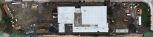 Aerial view of a construction site with a large rectangular building in progress, surrounded by dirt, vehicles, and equipment—perfect for a Capital Facilities Monthly Update.
